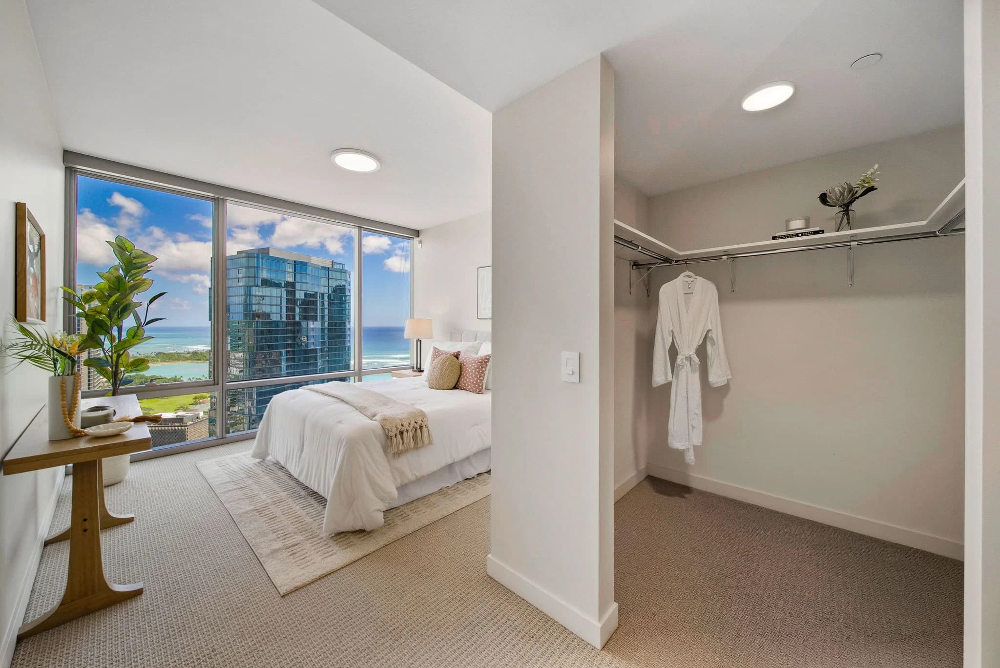 Primary bedroom with a walk-in closet and floor-to-ceiling windows framing the coastline.