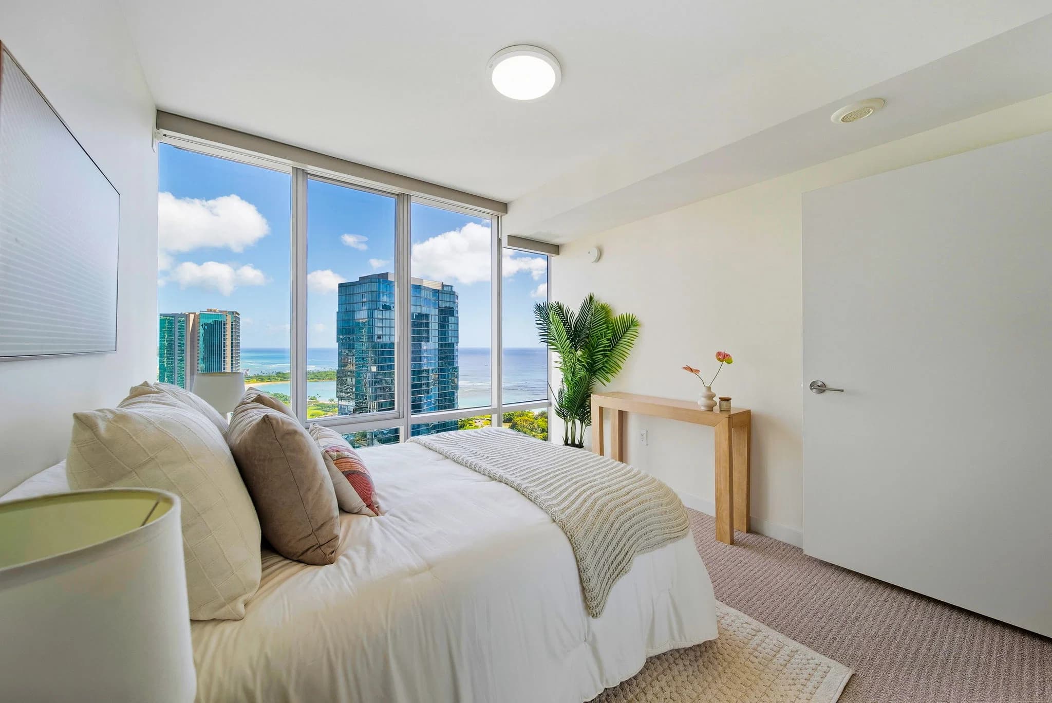 Bedroom with corner floor-to-ceiling windows and city views.