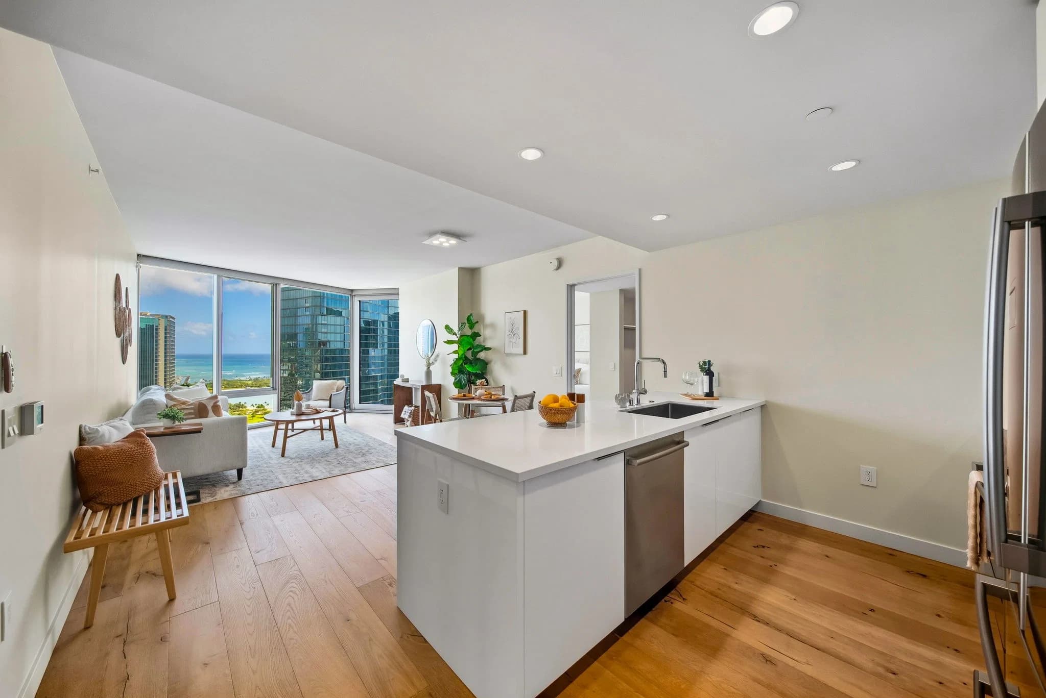 Open living and dining area with a kitchen island and floor-to-ceiling windows overlooking the coastline.
