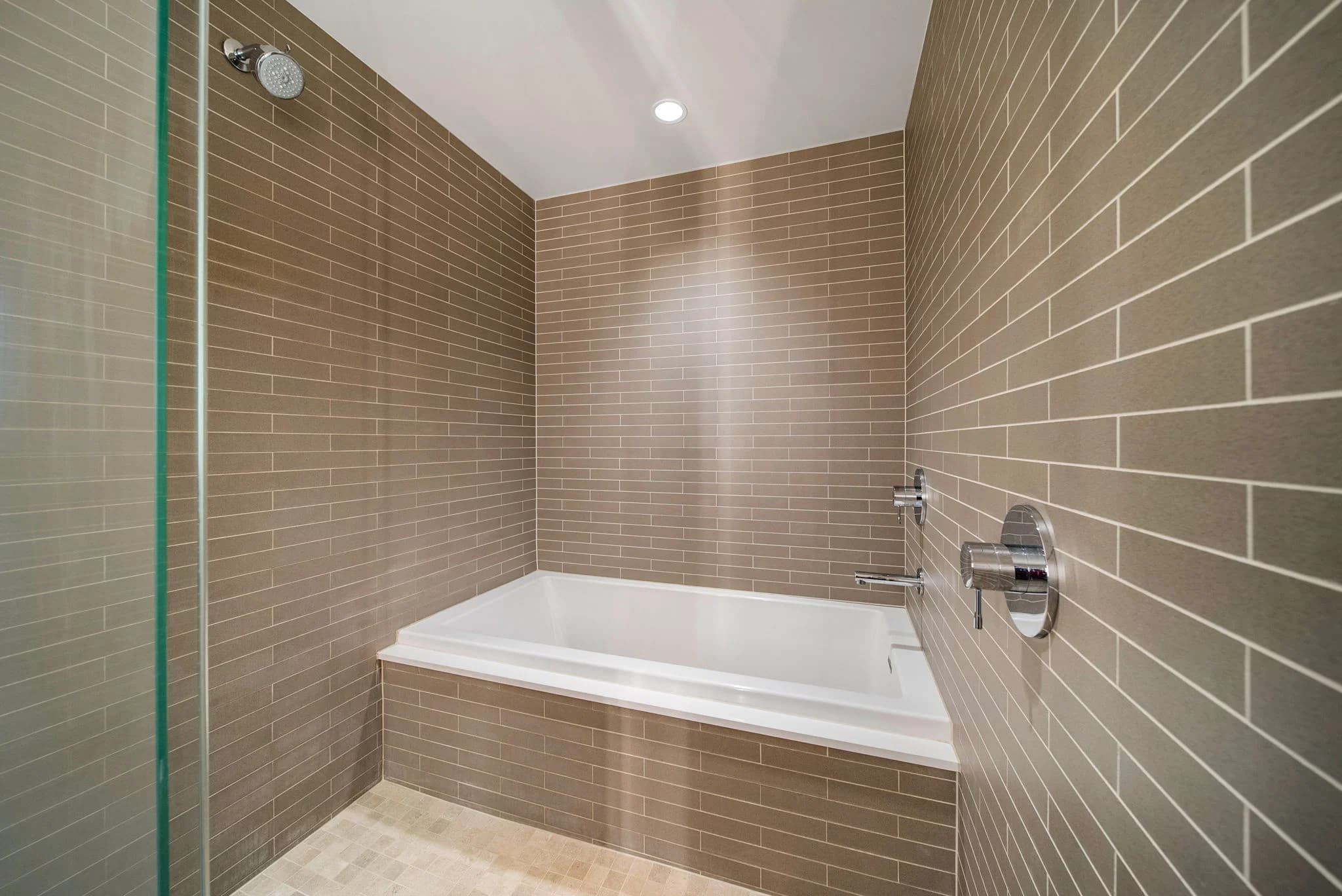 Bathroom with a soaking tub and tiled walls beside the walk-in shower.