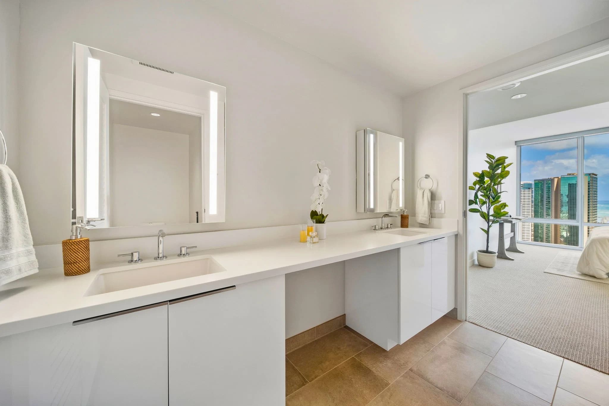 Primary bathroom with a dual vanity and backlit mirrors, opening to the bedroom and its views.