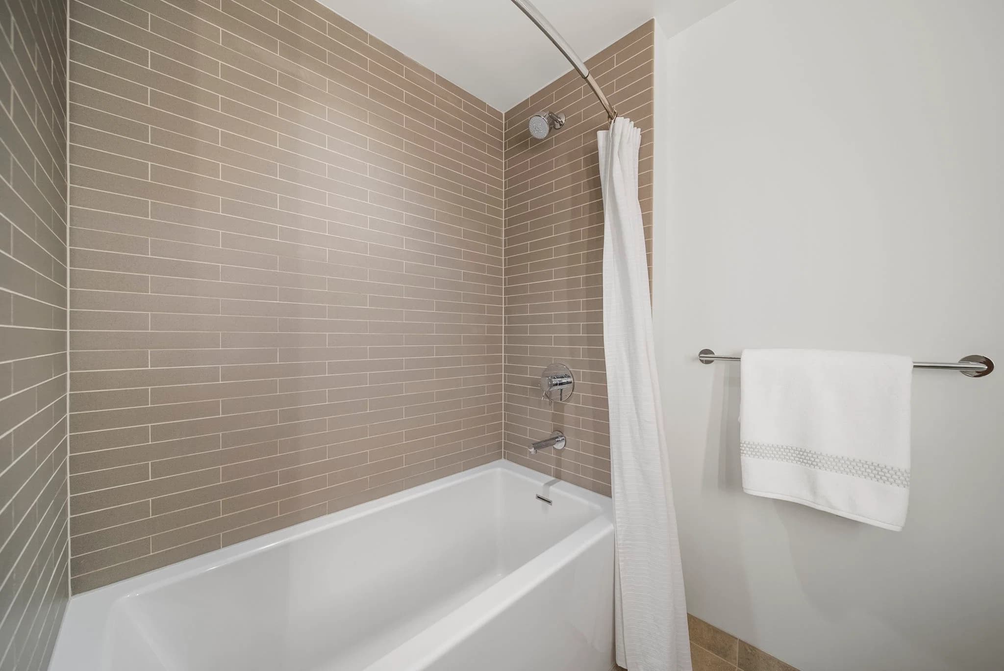 Bathroom with a shower-tub combination and tiled surround.